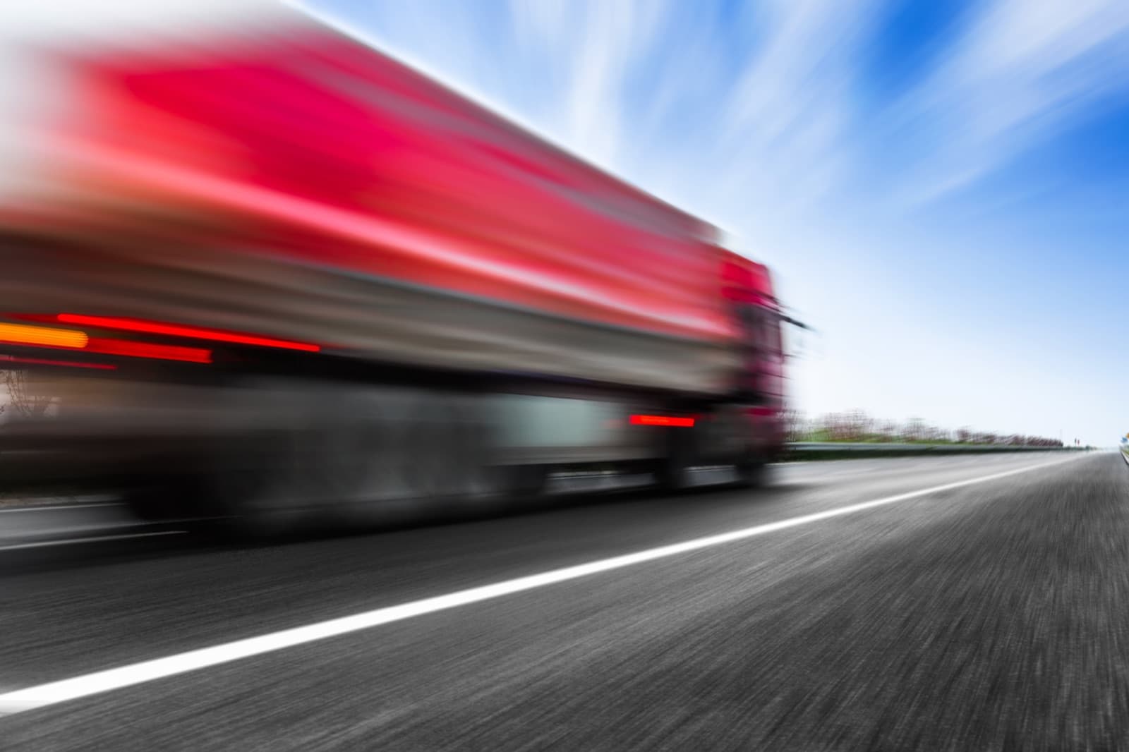 Red freight truck moving at speed on a highway